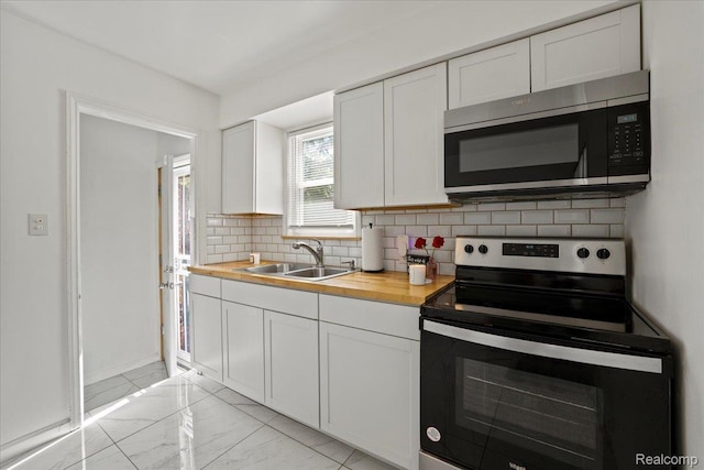 18247 Harlow St, Detroit, MI 48235 - kitchen with stainless steel appliances, butcher block countertops, light marble finish floors, backsplash, and white cabinetry