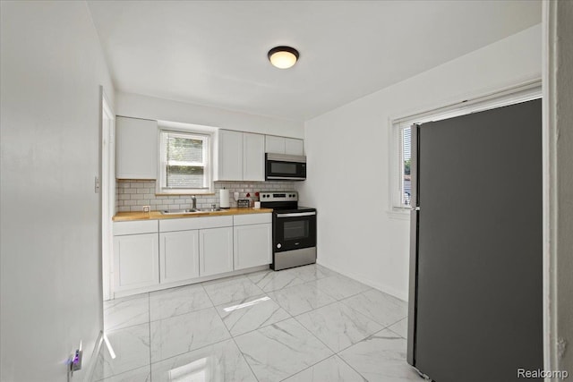 18247 Harlow St, Detroit, MI 48235 - kitchen featuring appliances with stainless steel finishes, butcher block countertops, white cabinetry, and light marble finish flooring