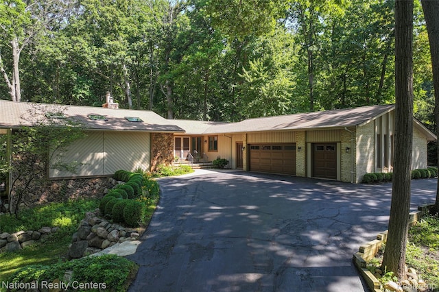 7500 Deerhill Dr, Clarkston, MI 48346 - mid-century inspired home with an attached garage, driveway, stone siding, and a chimney