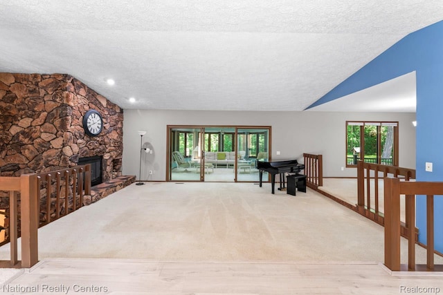 7500 Deerhill Dr, Clarkston, MI 48346 - unfurnished living room with a textured ceiling, a fireplace, lofted ceiling, wood finished floors, and carpet