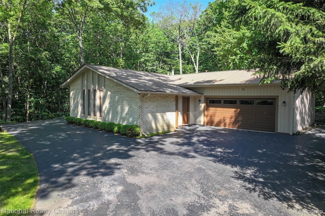 7500 Deerhill Dr, Clarkston, MI 48346 - view of home's exterior with asphalt driveway, an attached garage, brick siding, and roof with shingles