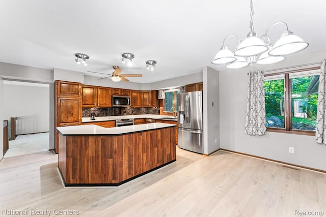 7500 Deerhill Dr, Clarkston, MI 48346 - kitchen with stainless steel appliances, light wood-type flooring, decorative backsplash, a chandelier, and a center island