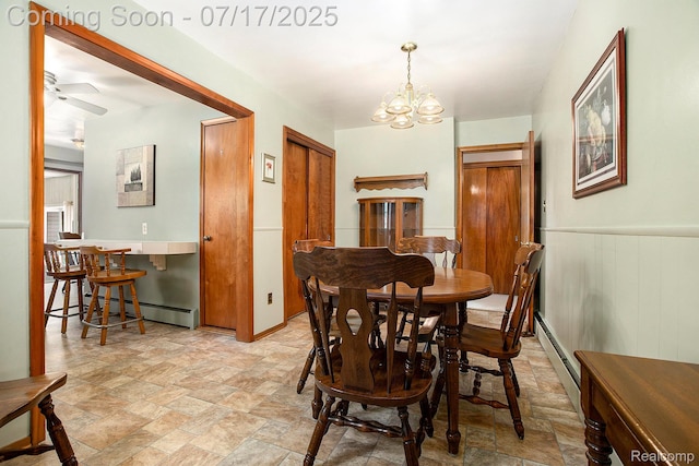 22950 Koths St, Taylor, MI 48180 - dining room with a baseboard heating unit, stone finish floors, a chandelier, wainscoting, and a ceiling fan