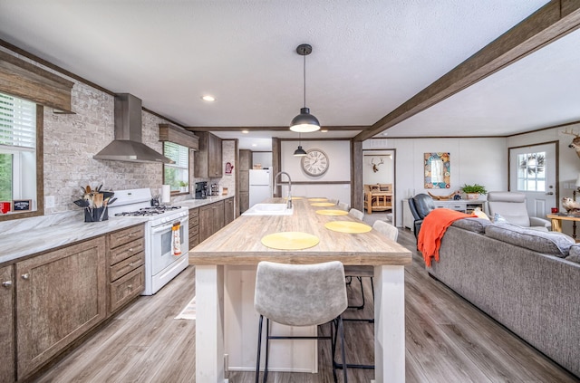 17648 Lost Lake Rd, Barryton, MI 49305 - kitchen with wall chimney range hood, white appliances, light wood finished floors, healthy amount of natural light, and beamed ceiling