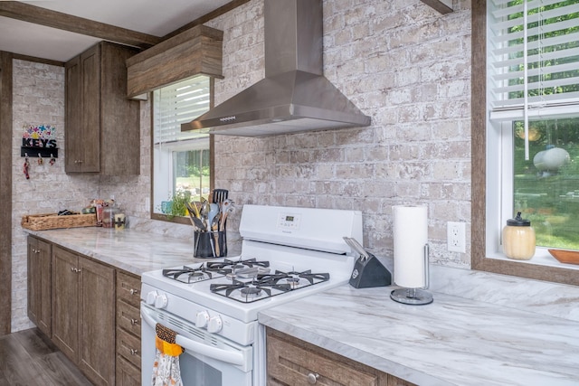 17648 Lost Lake Rd, Barryton, MI 49305 - kitchen with white range with gas stovetop, wall chimney exhaust hood, dark wood-style floors, beamed ceiling, and brown cabinetry