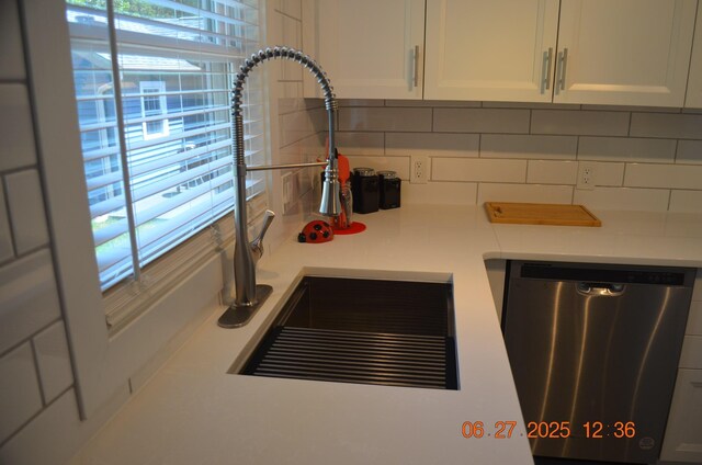 403 Hoover Ave, Benton Harbor, MI 49022 - kitchen view of stainless steel dishwasher, decorative backsplash, light countertops, and white cabinetry
