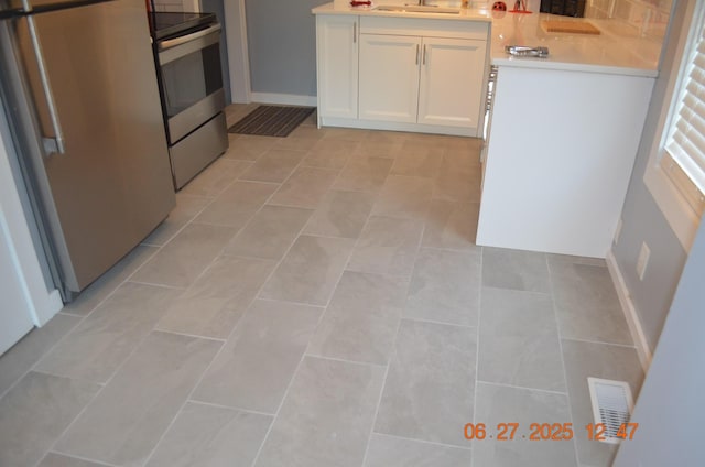 403 Hoover Ave, Benton Harbor, MI 49022 - kitchen featuring stainless steel electric stove, white cabinetry, fridge, and light countertops