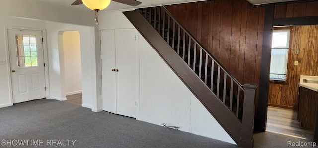 9825 Willow Ct, Clay, MI 48001 - stairway with ceiling fan, carpet, arched walkways, and wooden walls