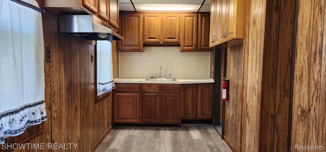 9825 Willow Ct, Clay, MI 48001 - kitchen with under cabinet range hood, light wood-style flooring, light countertops, and brown cabinets