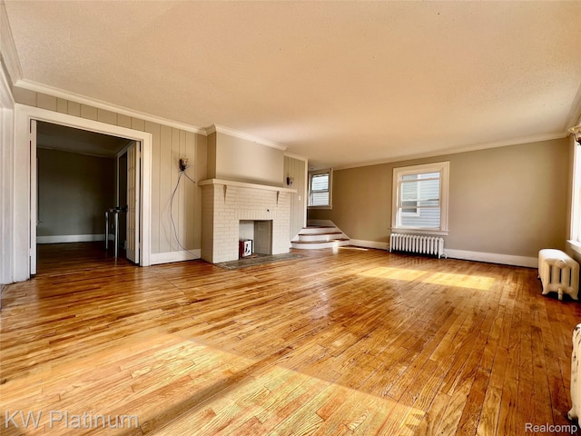 2109 Military St, Port Huron, MI 48060 - unfurnished living room featuring radiator, ornamental molding, a brick fireplace, and light wood-style flooring