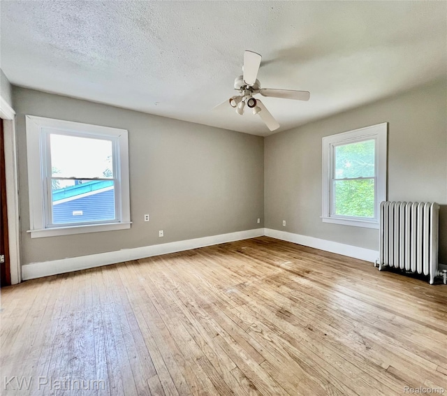 2109 Military St, Port Huron, MI 48060 - empty room featuring radiator heating unit, wood-type flooring, and a ceiling fan