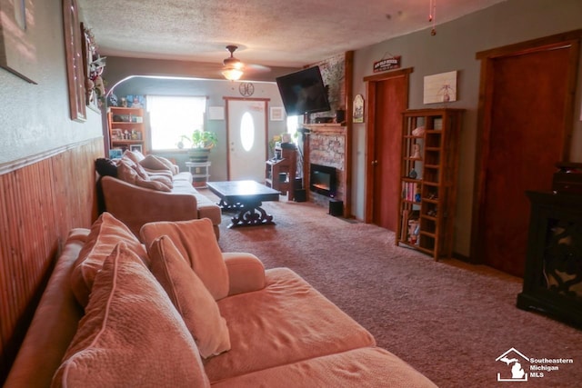 5985 Shady Ln, Newport, MI 48166 - carpeted living area with a ceiling fan, a stone fireplace, a textured ceiling, wainscoting, and wood walls