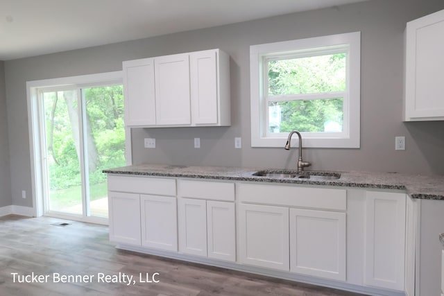 518 S Sullivan Ave, Fremont, MI 49412 - kitchen featuring white cabinetry, light stone countertops, healthy amount of natural light, and light wood-style flooring