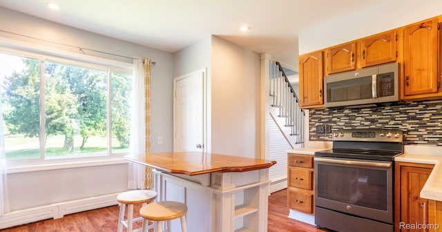 6550 Black River Rd, Croswell, MI 48422 - kitchen featuring stainless steel appliances, light wood-style floors, decorative backsplash, light countertops, and brown cabinetry