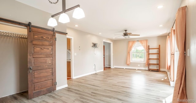 6550 Black River Rd, Croswell, MI 48422 - unfurnished bedroom featuring a barn door, light wood-style flooring, baseboard heating, and recessed lighting