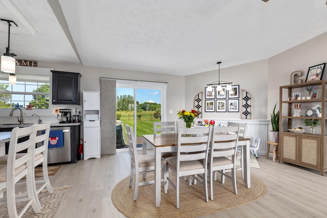 7241 Cherry Ave, Kewadin, MI 49648 - dining space featuring healthy amount of natural light, light wood-type flooring, and a textured ceiling