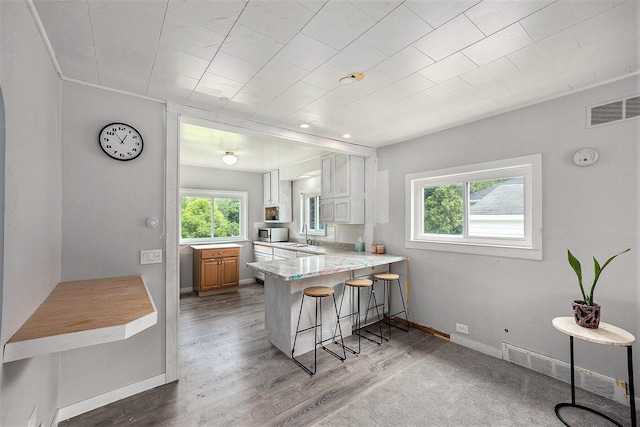 3477 Esson Dr, Grand Blanc, MI 48439 - kitchen featuring a kitchen breakfast bar, light countertops, wood finished floors, a peninsula, and stainless steel microwave