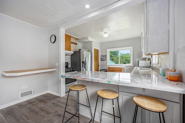 3477 Esson Dr, Grand Blanc, MI 48439 - kitchen featuring stainless steel appliances, dark wood-style flooring, a peninsula, under cabinet range hood, and a breakfast bar