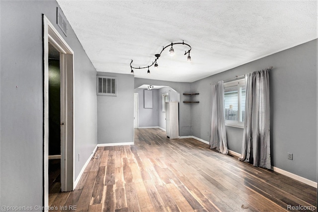 58 Yeamans St, Mount Clemens, MI 48043 - unfurnished living room featuring wood-type flooring, rail lighting, arched walkways, and a textured ceiling