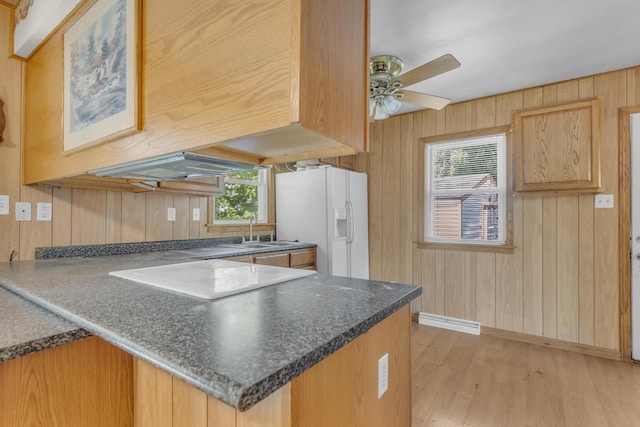 1196 S Dettman Rd, Jackson, MI 49203 - kitchen with white refrigerator with ice dispenser, light wood-style flooring, dark countertops, wooden walls, and a peninsula
