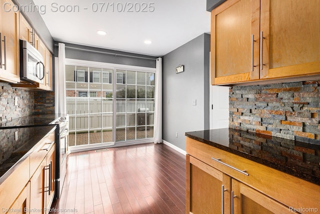42173 Pellston Dr, Northville, MI 48167 - kitchen featuring stainless steel appliances, decorative backsplash, dark wood finished floors, recessed lighting, and dark stone counters