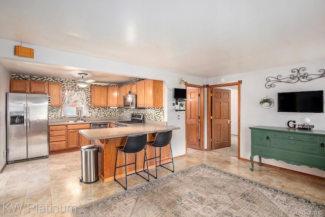 1509 Allen Rd, Kimball, MI 48074 - kitchen with appliances with stainless steel finishes, a peninsula, tasteful backsplash, a breakfast bar area, and brown cabinetry