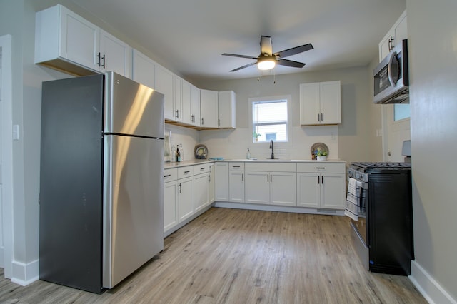 609 W Biddle St, Jackson, MI 49203 - kitchen with appliances with stainless steel finishes, a ceiling fan, light wood-style flooring, white cabinets, and tasteful backsplash