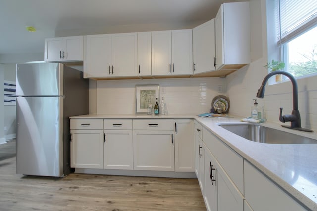 609 W Biddle St, Jackson, MI 49203 - kitchen with freestanding refrigerator, white cabinets, decorative backsplash, and light wood-style flooring