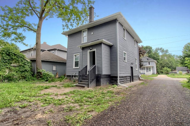 609 W Biddle St, Jackson, MI 49203 - rear view of house featuring entry steps and a chimney