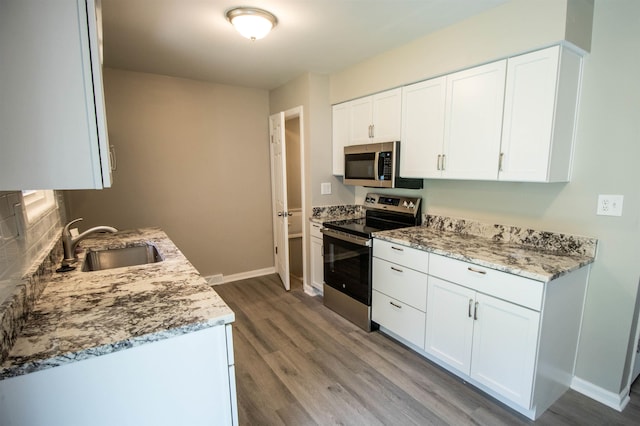 3745 Holly Ave, Flint, MI 48506 - kitchen featuring stainless steel appliances, light wood-style floors, white cabinetry, light stone counters, and backsplash