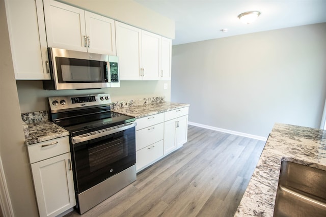 3745 Holly Ave, Flint, MI 48506 - kitchen featuring appliances with stainless steel finishes, light wood-type flooring, white cabinets, and light stone counters
