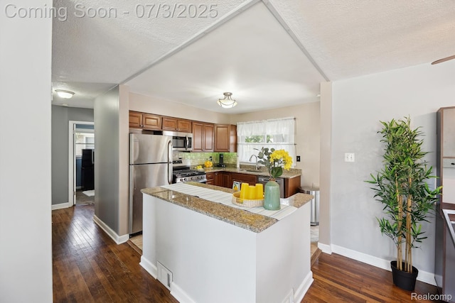 29934 Tamarack Dr, Gibraltar, MI 48134 - kitchen featuring stainless steel appliances, brown cabinetry, dark wood-type flooring, backsplash, and a textured ceiling
