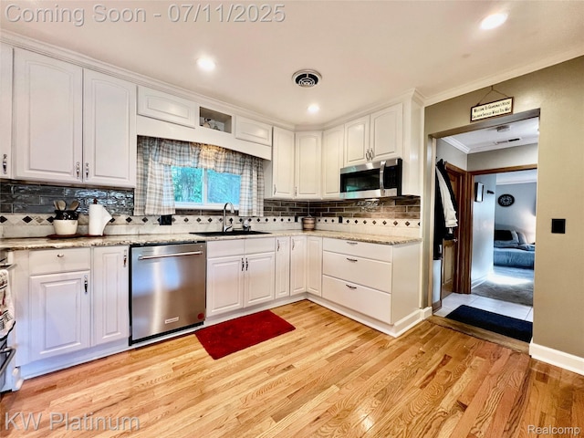 7135 Gardner Line Rd, Lexington, MI 48450 - kitchen with appliances with stainless steel finishes, light wood finished floors, white cabinetry, backsplash, and ornamental molding