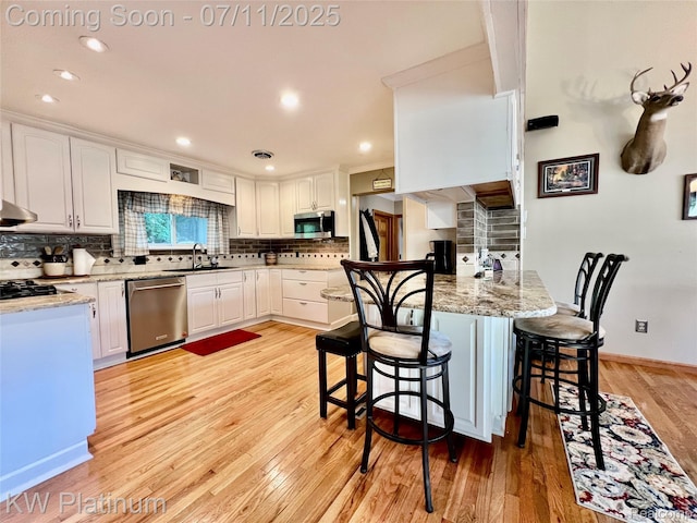 7135 Gardner Line Rd, Lexington, MI 48450 - kitchen with appliances with stainless steel finishes, a peninsula, light wood-type flooring, backsplash, and white cabinetry