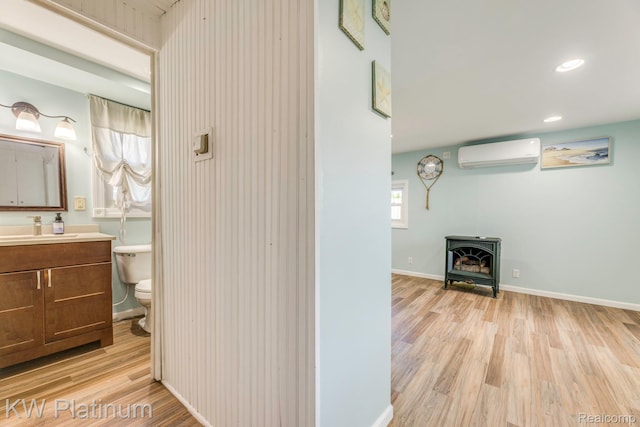 7377 Dogwood Rd, Lexington, MI 48450 - bathroom with a wall unit AC, wood finished floors, vanity, recessed lighting, and a wood stove