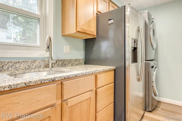 7377 Dogwood Rd, Lexington, MI 48450 - kitchen featuring stainless steel fridge, stacked washing machine and dryer, light wood-type flooring, light brown cabinets, and light stone countertops