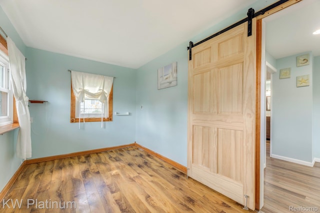 7377 Dogwood Rd, Lexington, MI 48450 - unfurnished bedroom featuring a barn door and light wood-style flooring