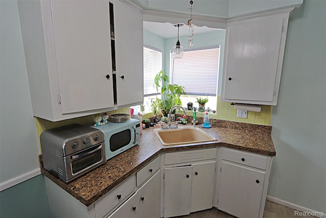 24271 Westhampton St, Oak Park, MI 48237 - kitchen with decorative backsplash, dark countertops, white cabinetry, and hanging light fixtures