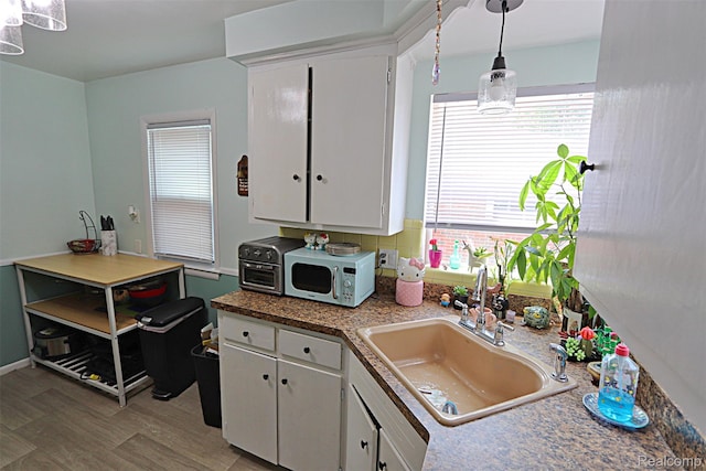 24271 Westhampton St, Oak Park, MI 48237 - kitchen with white cabinetry, decorative light fixtures, and light wood-style flooring