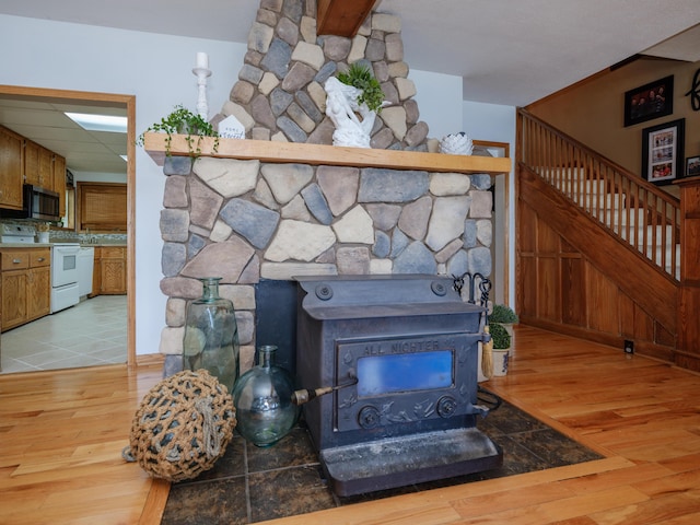 44850 Woodman Dr, Paw Paw, MI 49079 - detailed view of electric range, a wood stove, stainless steel microwave, and wood finished floors