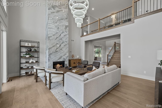 1760 Hamilton Dr, Bloomfield Hills, MI 48302 - living room featuring a towering ceiling, a fireplace, stairs, wood finished floors, and a chandelier