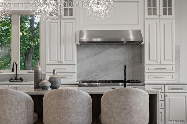 1760 Hamilton Dr, Bloomfield Hills, MI 48302 - kitchen with wall chimney range hood, a chandelier, white cabinets, glass insert cabinets, and light countertops