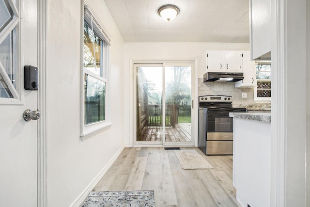 46 N 31st St, Battle Creek, MI 49015 - kitchen with electric stove, under cabinet range hood, light wood finished floors, white cabinets, and healthy amount of natural light