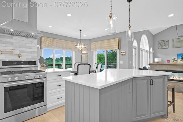 2545 Hartun Dr, Brighton, MI 48114 - kitchen with stainless steel gas stove, wall chimney exhaust hood, gray cabinetry, light countertops, and light wood finished floors