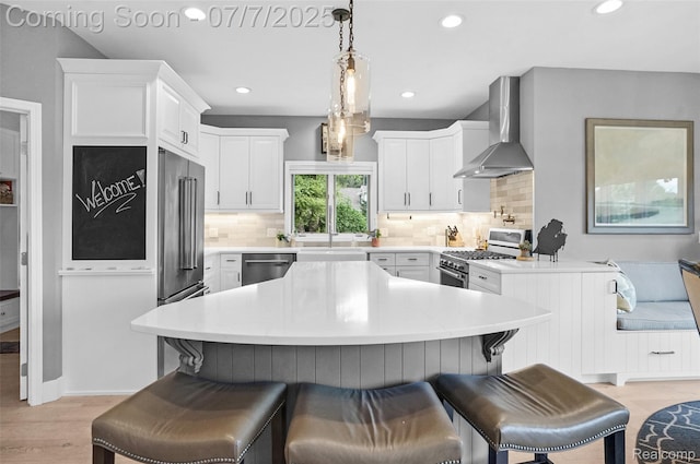 2545 Hartun Dr, Brighton, MI 48114 - kitchen featuring wall chimney range hood, stainless steel appliances, a breakfast bar area, white cabinetry, and backsplash