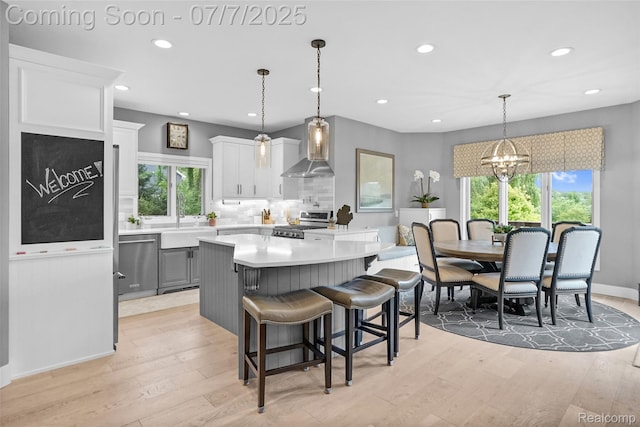 2545 Hartun Dr, Brighton, MI 48114 - kitchen with wall chimney range hood, appliances with stainless steel finishes, light countertops, healthy amount of natural light, and recessed lighting
