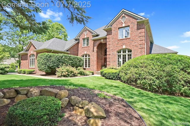2545 Hartun Dr, Brighton, MI 48114 - view of front facade with brick siding, a front lawn, and a shingled roof