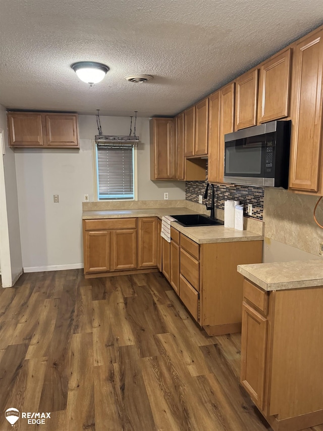 11454 Haven St, Clio, MI 48420 - kitchen with stainless steel microwave, dark wood-style flooring, light countertops, a textured ceiling, and backsplash