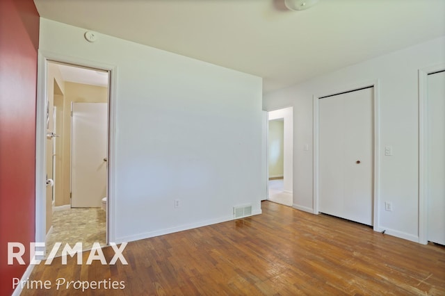 2524 Whitemore Pl, Saginaw, MI 48602 - unfurnished bedroom featuring wood finished floors, two closets, and ensuite bath