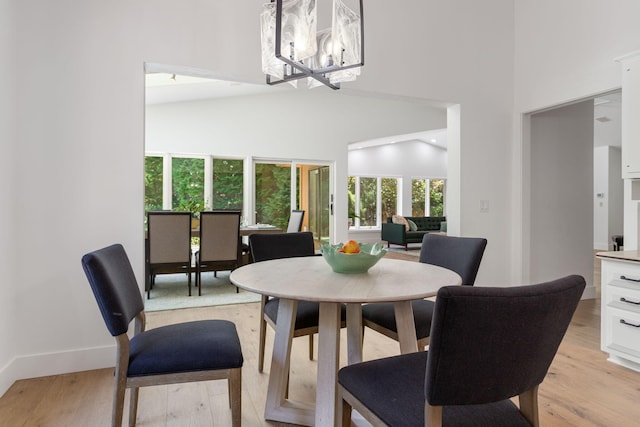 295 N Lakeshore Dr, Holland, MI 49424 - dining space with light wood-style flooring, a chandelier, and a high ceiling